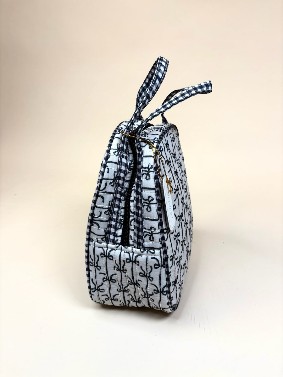 Side view of the Simply Southern Black Bow Quilted Lunch Bag showcasing its insulated profile, quilted bow print, dual handles, and zip-top closure on a cream studio background.