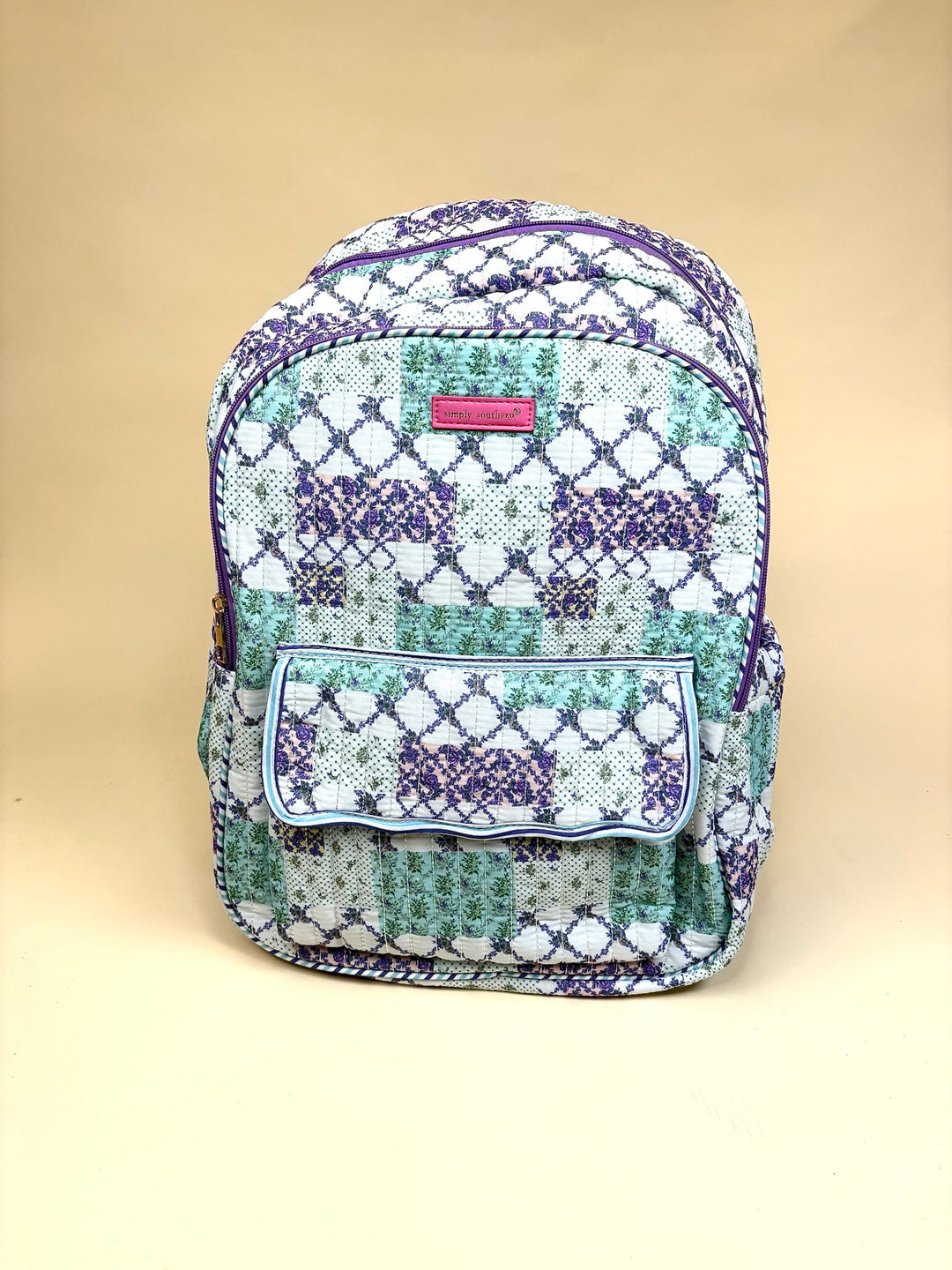 Simply Southern Trail Patch Quilted Backpack featuring a colorful patchwork floral print, front flap pocket, side pockets, and padded shoulder straps.