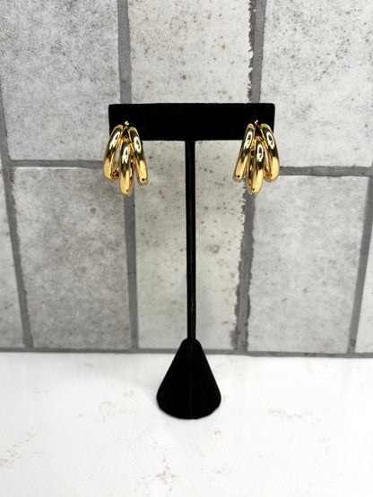 Gold triple hoop earrings on black display stand – trendy statement hoop earrings for women