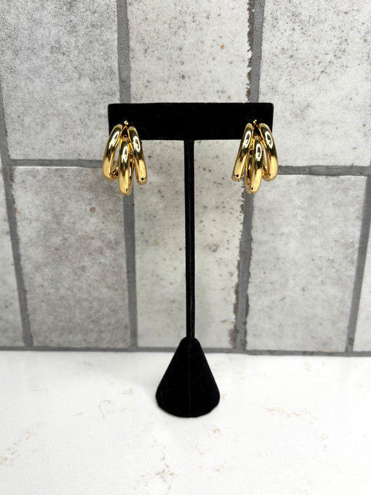 Gold triple hoop earrings on black display stand – trendy statement hoop earrings for women