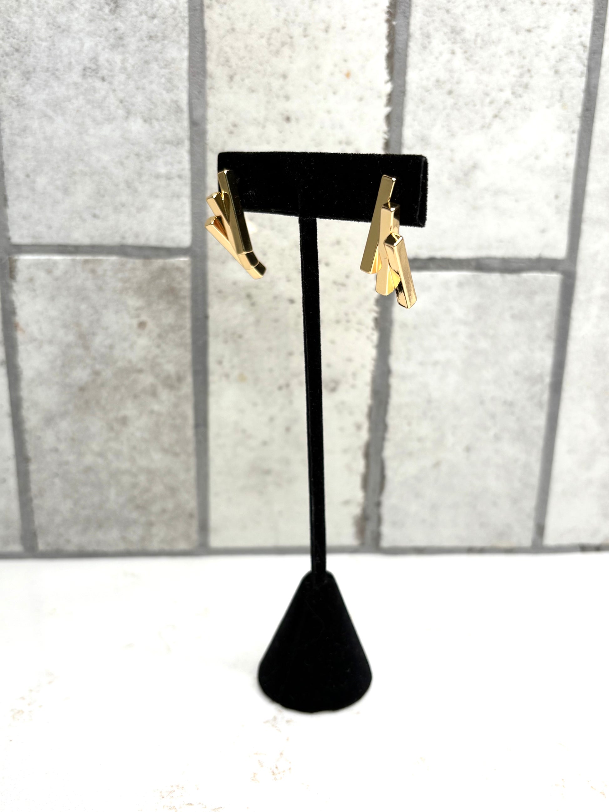 Gold geometric bar drop earrings on black stand – modern minimalist women’s boutique jewelry