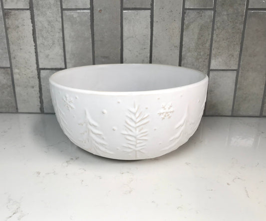 White ceramic bowl with leaf patterns on a white countertop with a tiled wall background
