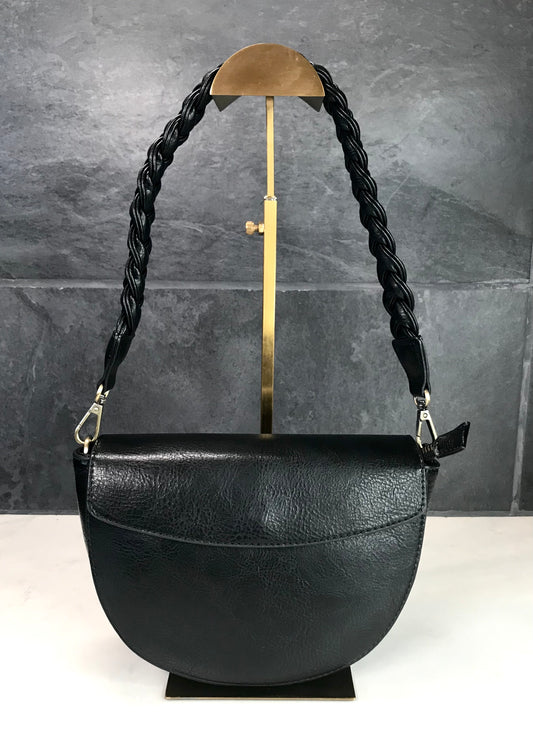 Black leather handbag with braided handle on a stand against a gray background