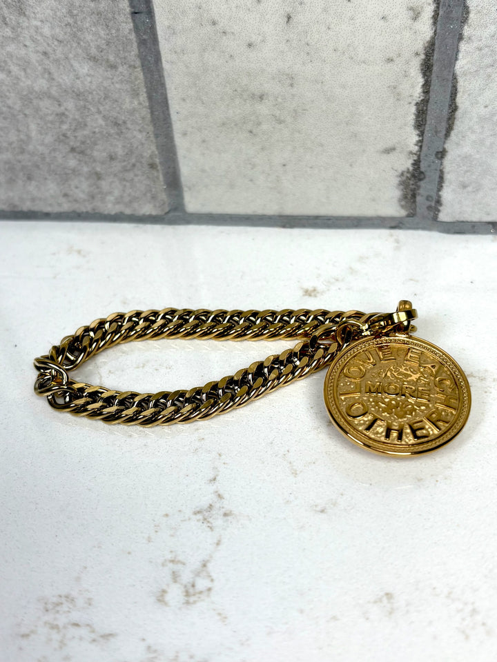 Gold chain with a round medallion on a marble surface with a tiled wall background