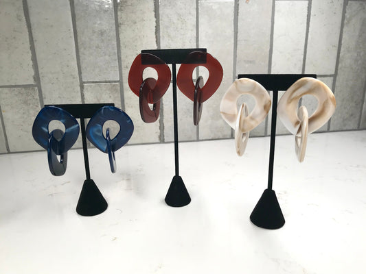 Set of earrings on black stands against a light background