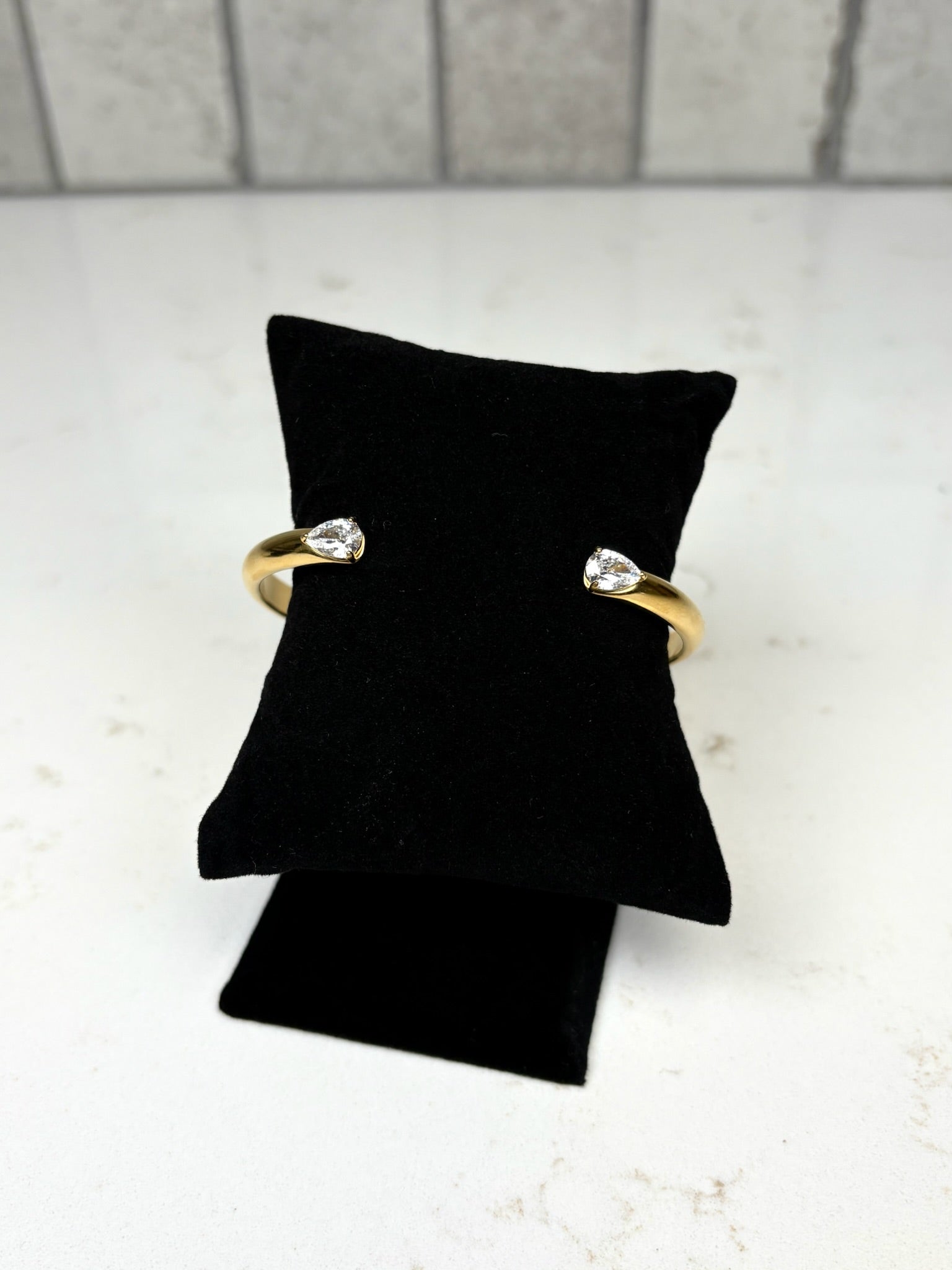 Chan Sutt Pearl gold open cuff bracelet with pear-shaped crystal ends on black display pillow