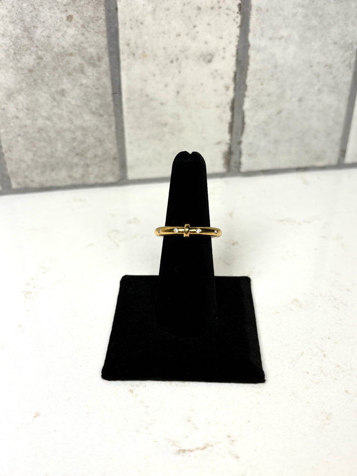 Gold bow detail ring with delicate clear crystal accents displayed on a black velvet jewelry stand.