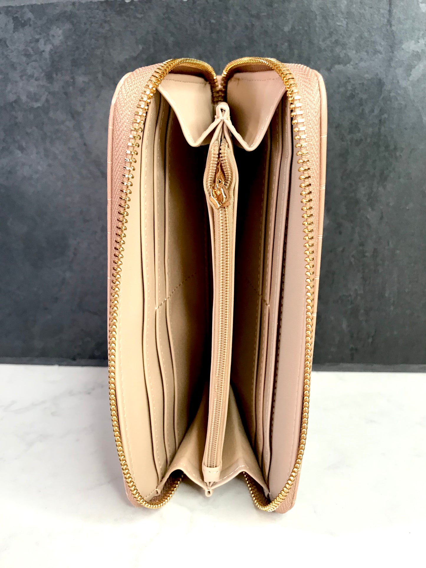 Beige Caroline Hill wallet with a zipper on a gray background