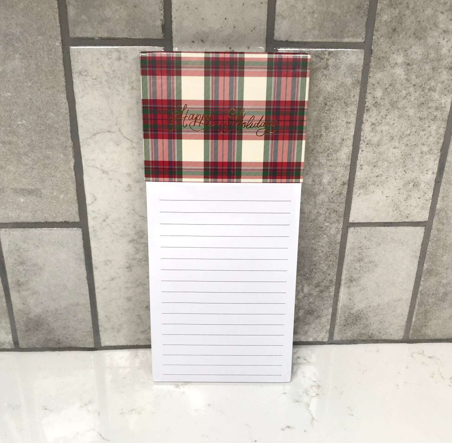 Notepad with plaid cover and lined pages on a tiled floor