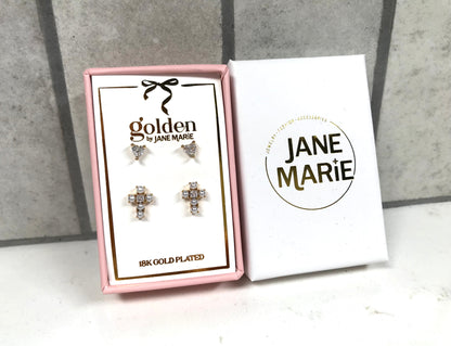 Kids 18K gold-plated stud earring set by Jane Marie, including crystal heart studs and clustered crystal cross studs, packaged in a pink gift box next to white Jane Marie branding sleeve.