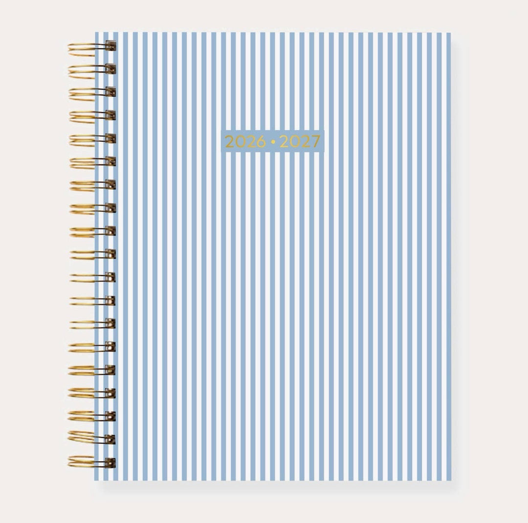 Elyse Breanne Designs 2026–2027 Academic Planner in the Blue Stripes pattern featuring classic light blue and white vertical stripes, gold spiral binding, and a durable soft-touch laminated cover.