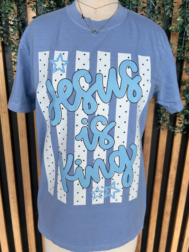 Close-up of washed denim Christian graphic tee with Jesus Is King print, polka dots, and star accents.