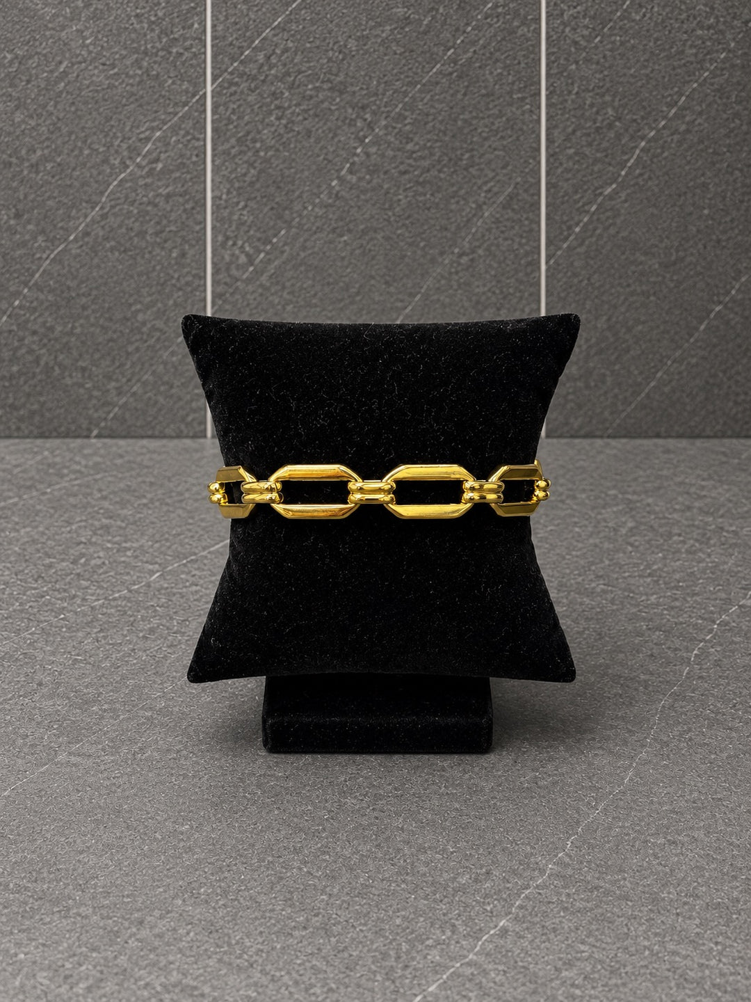Alex waterproof 18K gold plated stainless steel statement bracelet with oversized geometric links displayed on a black velvet bracelet pillow.