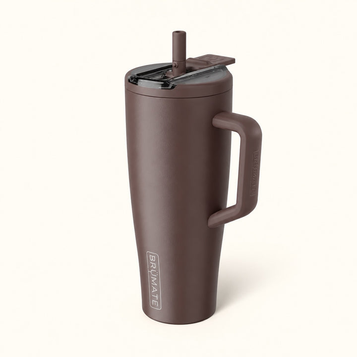 BrüMate Era Flip 40oz insulated straw tumbler in Java featuring a rich matte chocolate brown finish, coordinating carrying handle, covered flip-down straw lid shown open, and vertical BrüMate branding. The tall leakproof water tumbler features a cupholder-friendly base and is displayed against a soft cream studio background.
