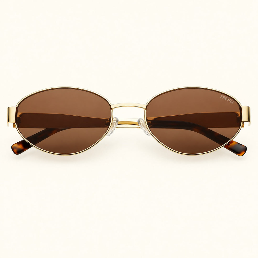 Front view of FREYRS Soho women's oval sunglasses in Gold/Brown featuring slim gold stainless steel frames, brown lenses, and tortoiseshell temple tips.