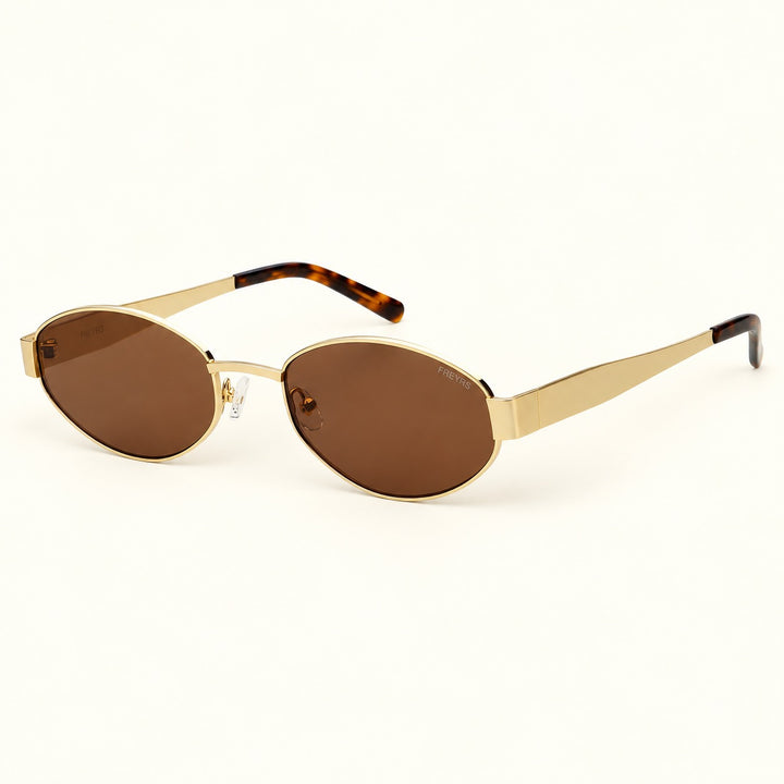 Angled view of FREYRS Soho Gold/Brown oval sunglasses showing the gold-tone metal temples, brown nylon lenses, clear nose pads, and tortoiseshell temple tips.