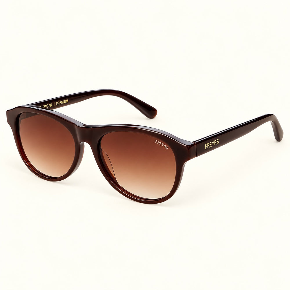 Angled view of FREYRS Remi Chocolate Brown sunglasses showing glossy acetate frames, brown gradient lenses, and matching temples with gold FREYRS branding.