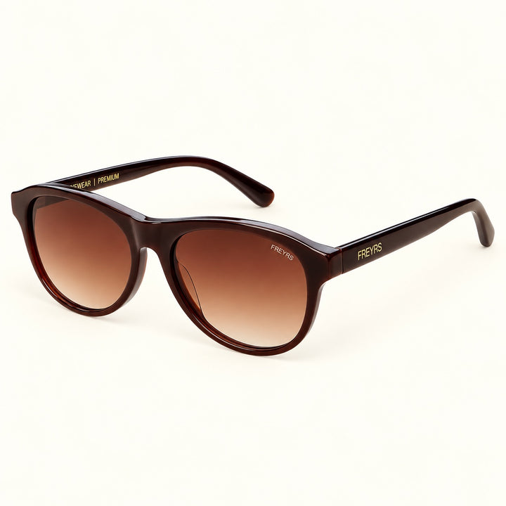 Angled view of FREYRS Remi Chocolate Brown sunglasses showing glossy acetate frames, brown gradient lenses, and matching temples with gold FREYRS branding.