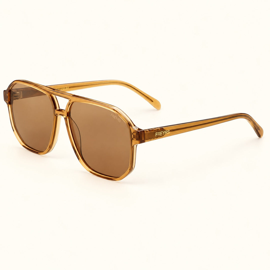 Angled view of FREYRS Billie Brown aviator sunglasses showing biodegradable translucent acetate frames, premium brown nylon lenses, double bridge, and FREYRS branded temples.