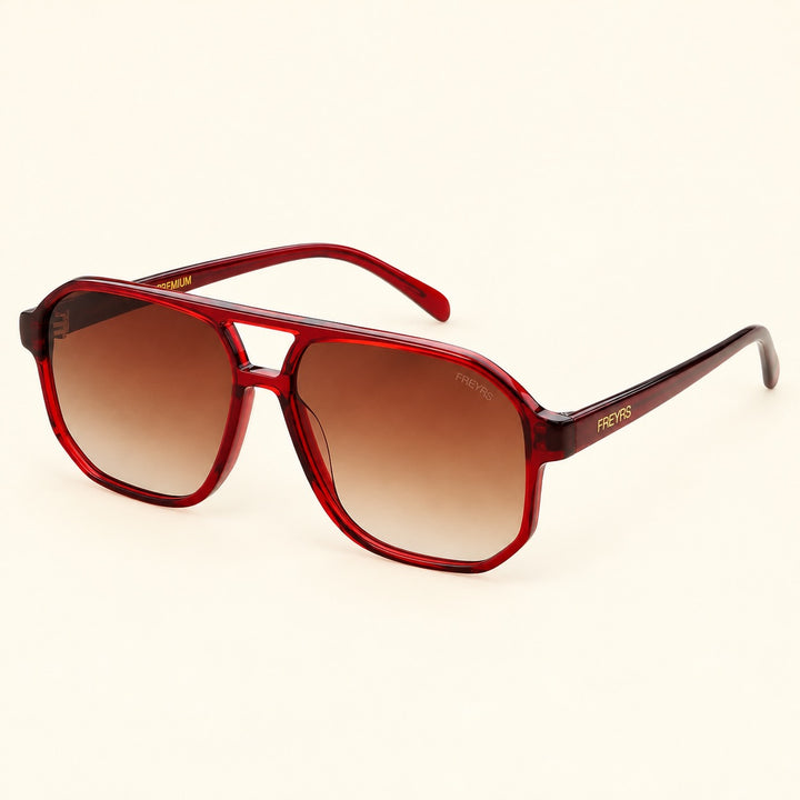 Angled view of FREYRS Billie Dark Cherry aviator sunglasses showing translucent red biodegradable acetate frames, brown gradient lenses, double bridge, and FREYRS branded temples.