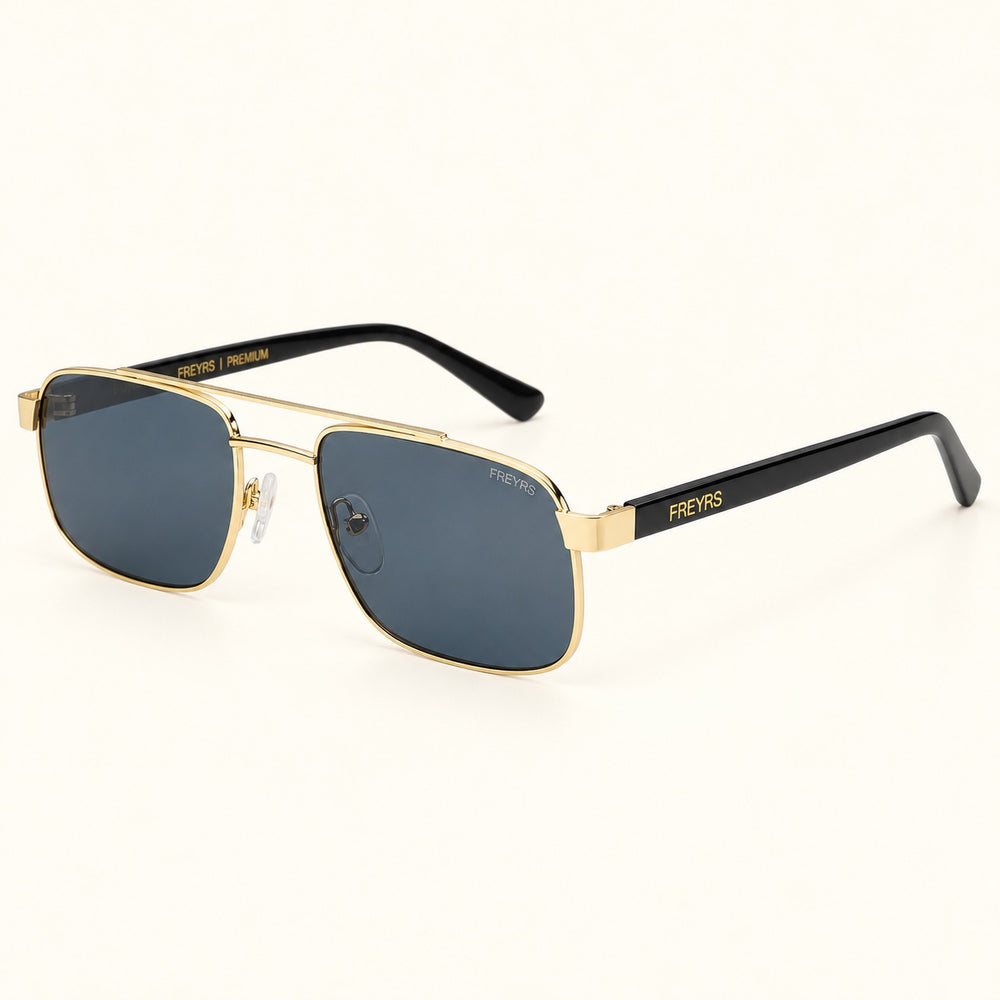 Angled view of FREYRS Vesper Gold / Gray aviator sunglasses showing lightweight gold-tone metal frames, gray lenses, clear nose pads, and black FREYRS branded temples.