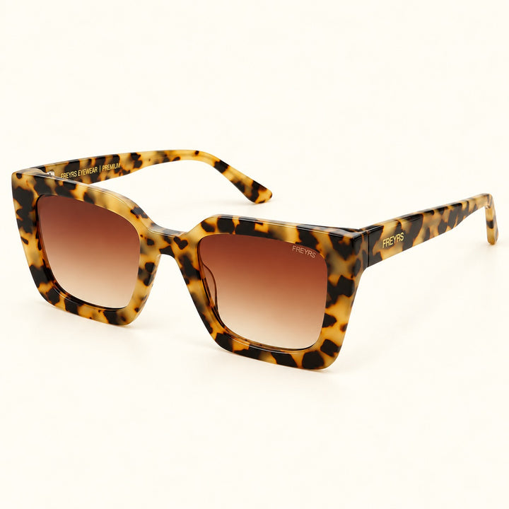 Angled view of FREYRS Coco Tortoise square sunglasses showing handmade tortoiseshell acetate frames, brown gradient lenses, wide patterned temples, and gold FREYRS branding.