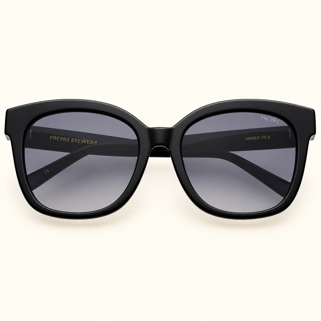Front view of FREYRS Amber women's cat eye sunglasses in Black featuring glossy black acetate frames, gray gradient lenses, and a flattering upswept silhouette.