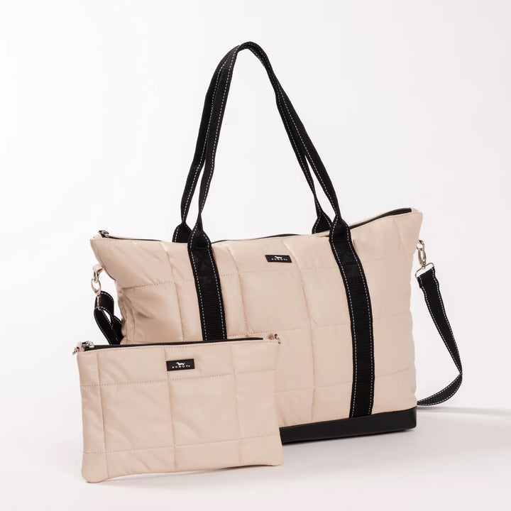 A quilted beige tote bag with black handles, trim, and base, shown alongside a matching zippered pouch on a clean white background.
