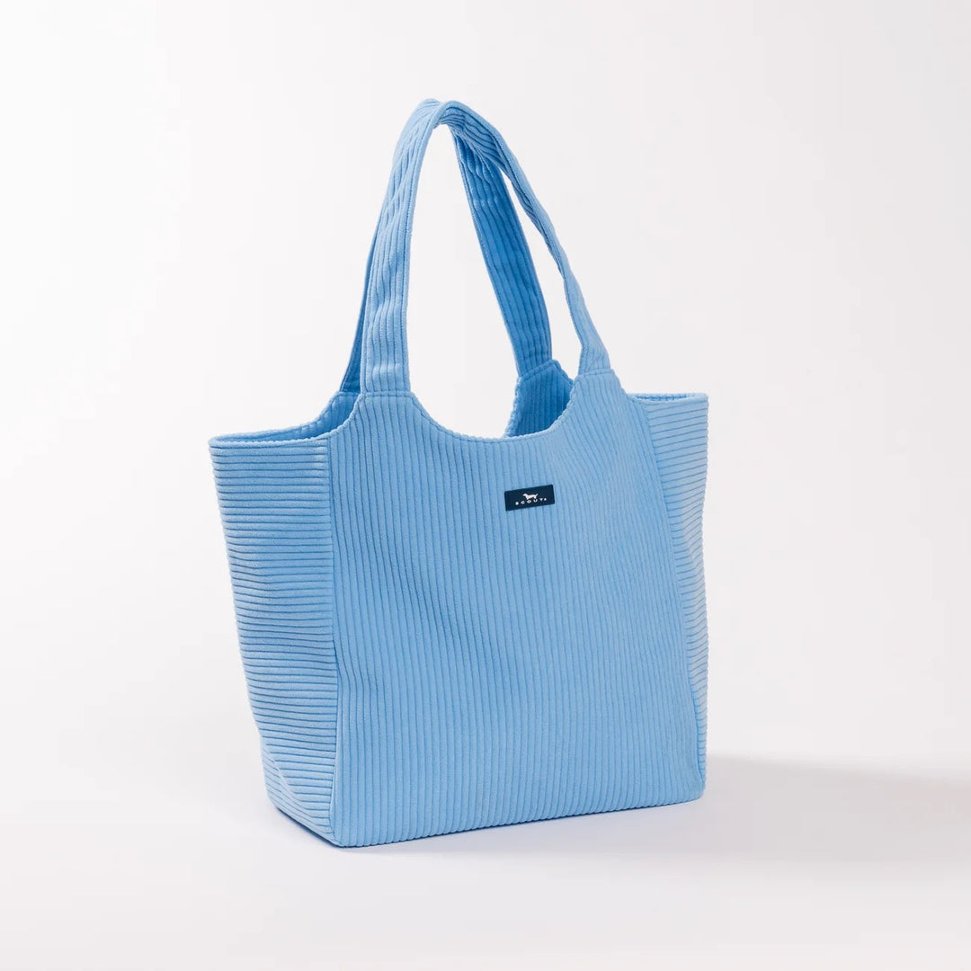 A light blue corduroy tote bag with dual shoulder straps and a small black brand label on the front, photographed on a clean white studio background.