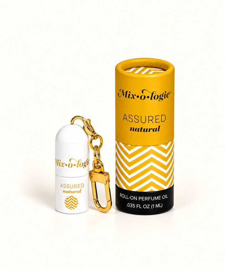Mixologie Assured Natural mini roll-on perfume keychain with gold clip and yellow chevron-patterned cylindrical packaging.