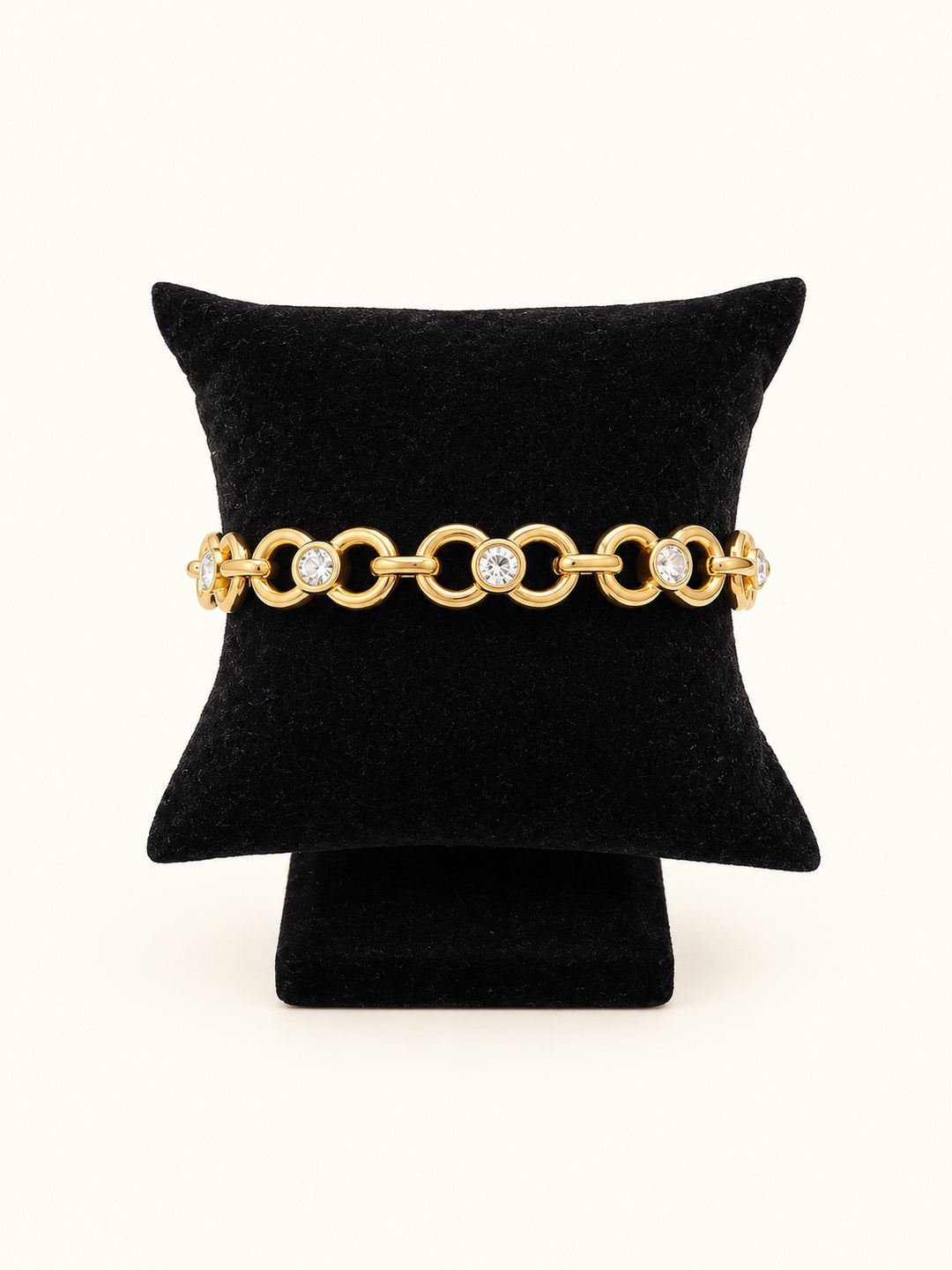 Savannah Gold Anklet and Bracelet featuring interlocking circular links with sparkling clear stones, crafted from 18K gold plated stainless steel and displayed on a black velvet jewelry pillow.