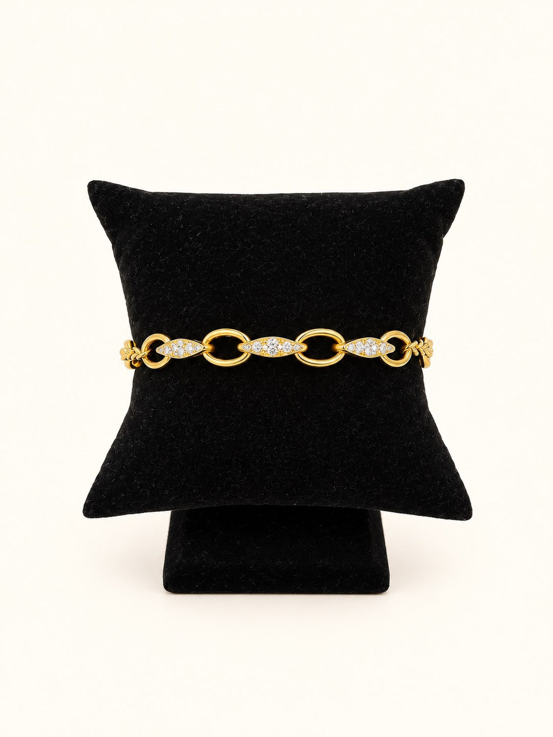 Blake Gold Chain Bracelet featuring polished oval links and sparkling clear stone accents in 18K gold plated stainless steel, displayed on a black velvet jewelry pillow.