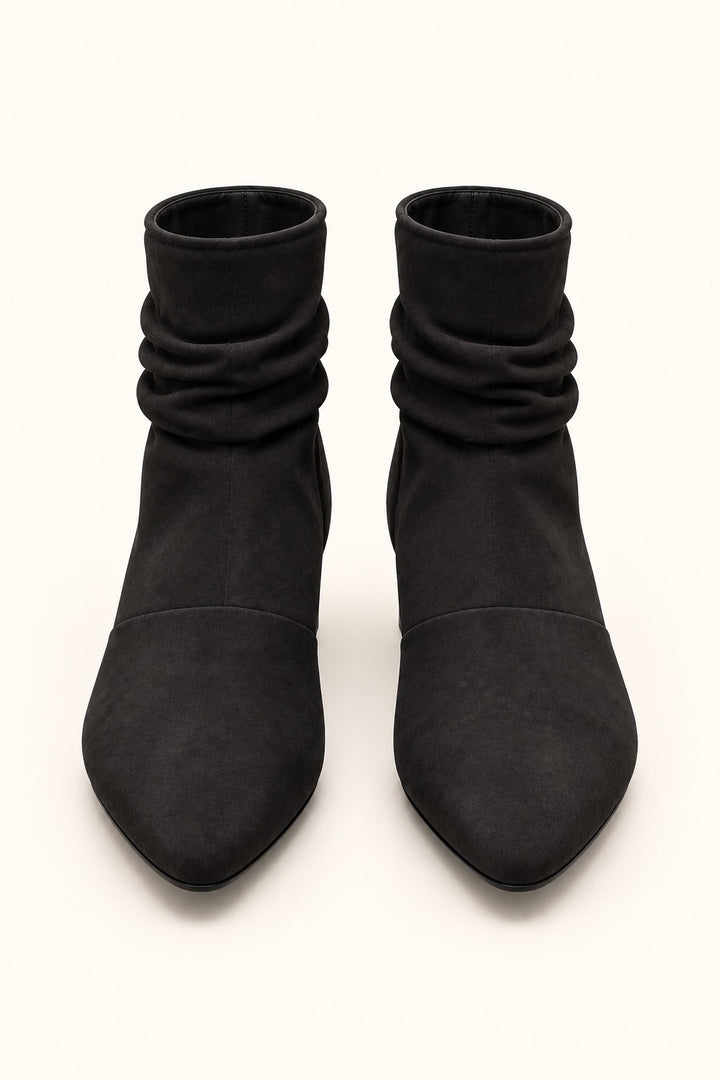 Front view of black pointed-toe slouch boots featuring gathered shafts and a soft suede finish.