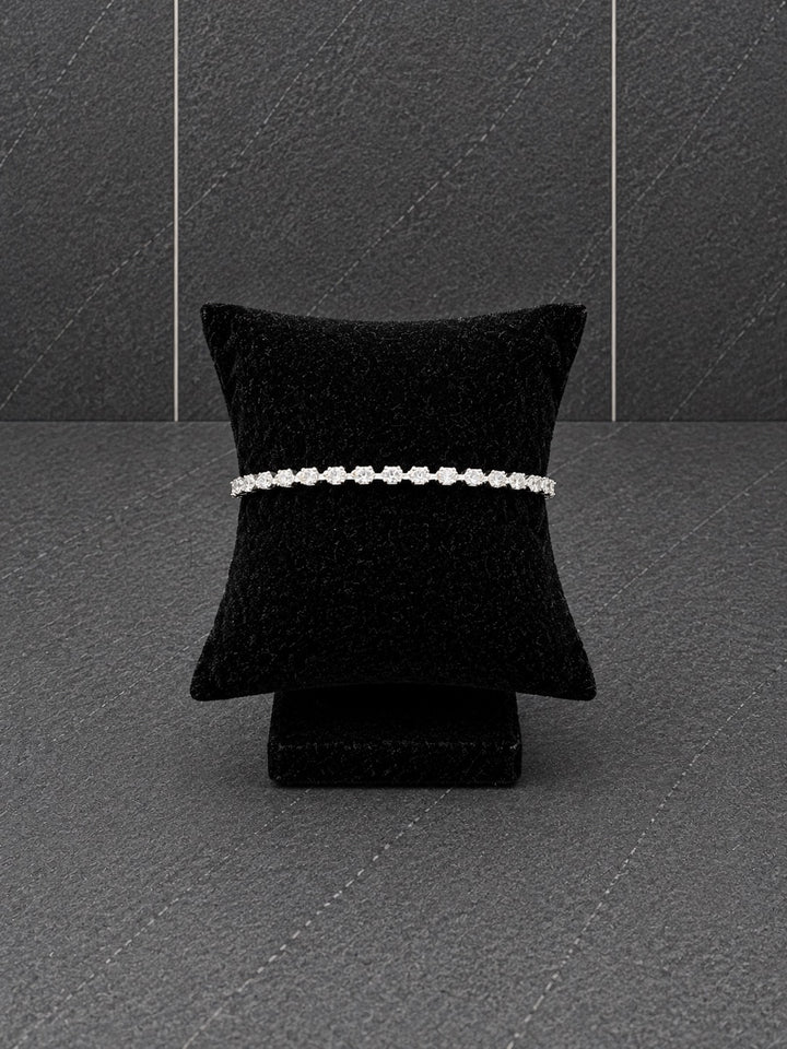 Silver-plated tennis bracelet featuring a continuous row of sparkling cubic zirconia stones displayed on a black velvet bracelet pillow.