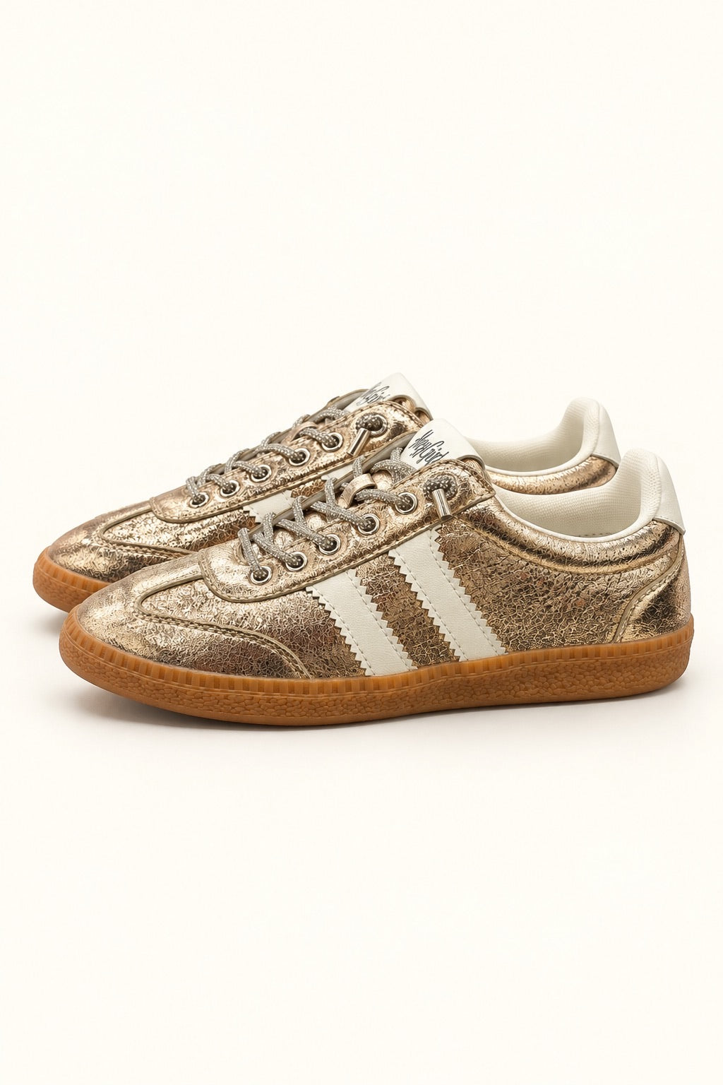 Corkys Heads Up women’s sneaker in Gold Metallic with white side stripes, rhinestone-accented laces, and gum sole.