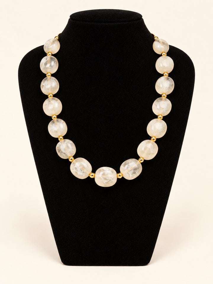 Lindon Cream Statement Beaded Necklace featuring oversized translucent ivory resin beads and gold-tone accents displayed on black velvet at Square 1 Boutique.