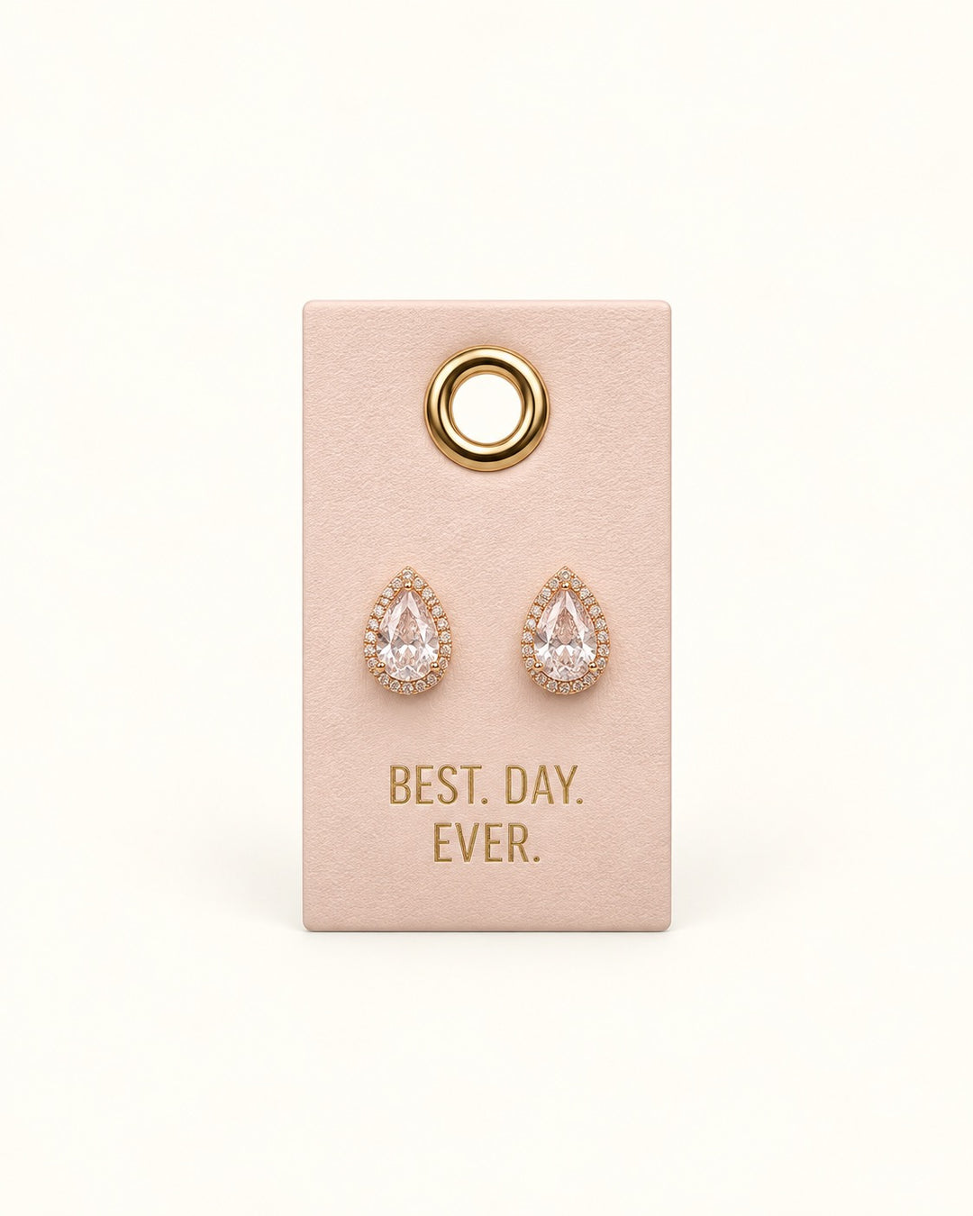 Clear teardrop crystal bridal stud earrings with sparkling rhinestone halos and gold-tone settings displayed on a blush Best Day Ever wedding leather tag.