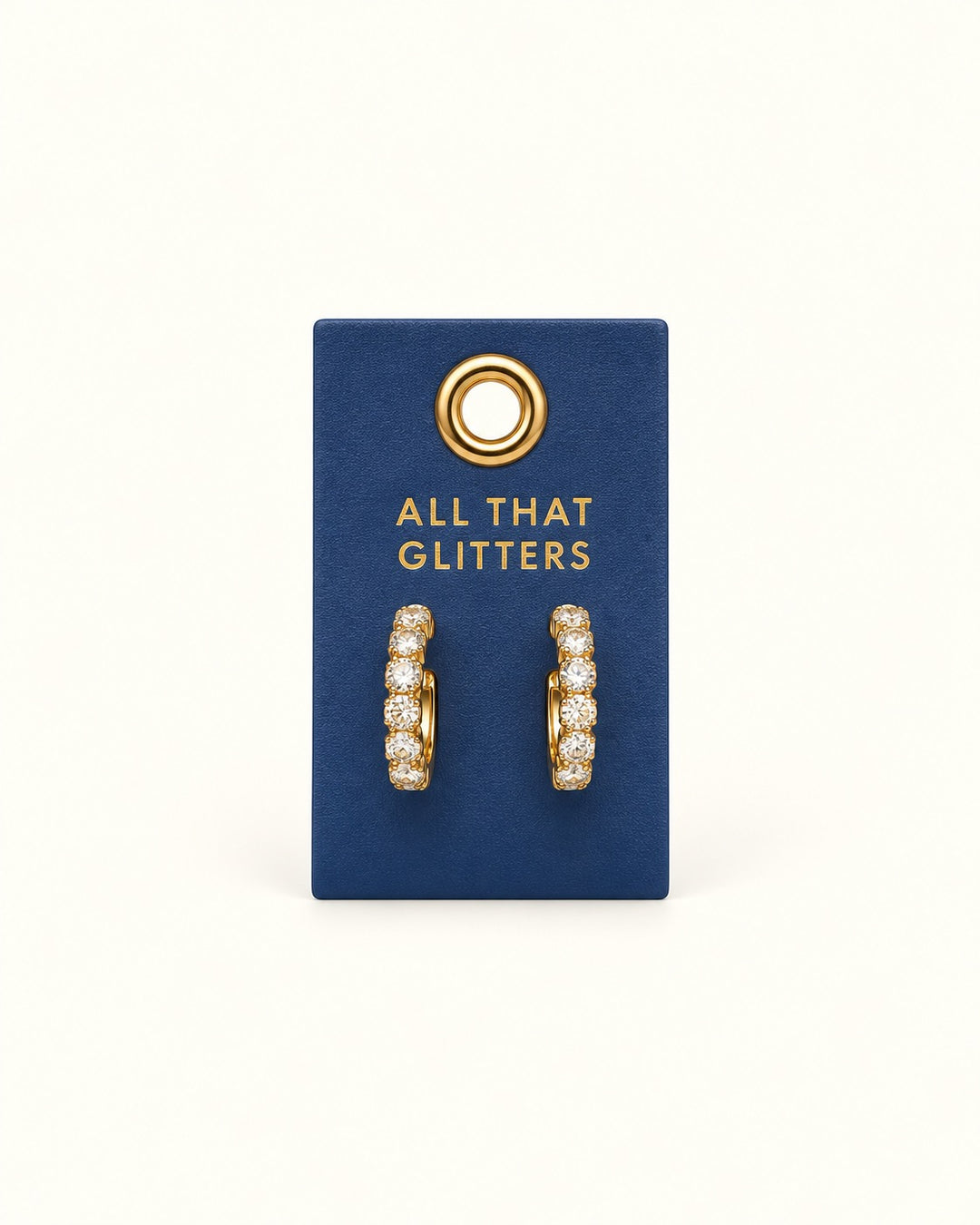 Gold-tone petite hoop earrings with sparkling clear crystal accents displayed on a navy blue All That Glitters Palm Beach leather jewelry tab.