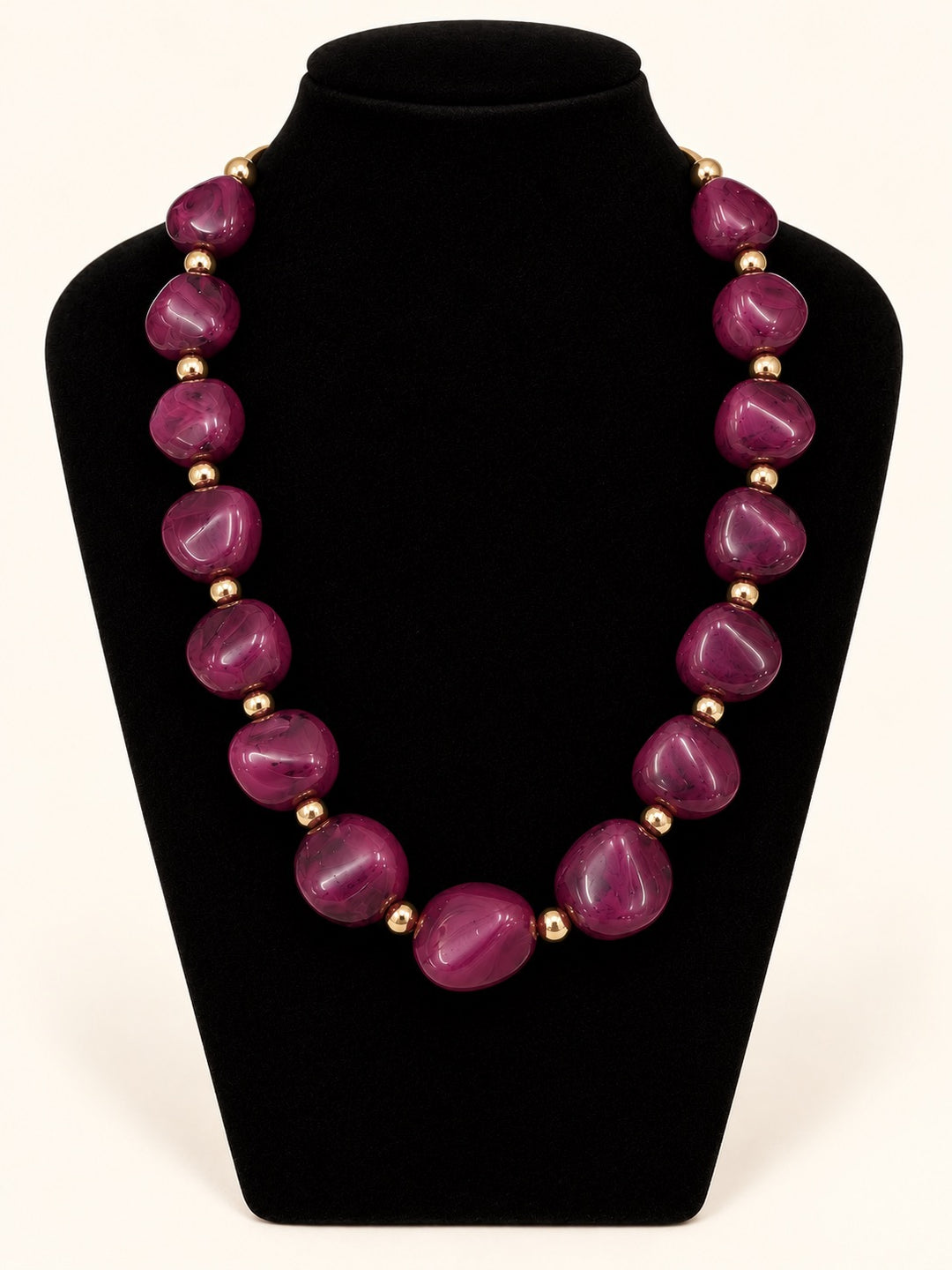 Lindon Plum Statement Necklace featuring oversized glossy plum resin beads and polished gold-tone spacers on a black velvet jewelry display.