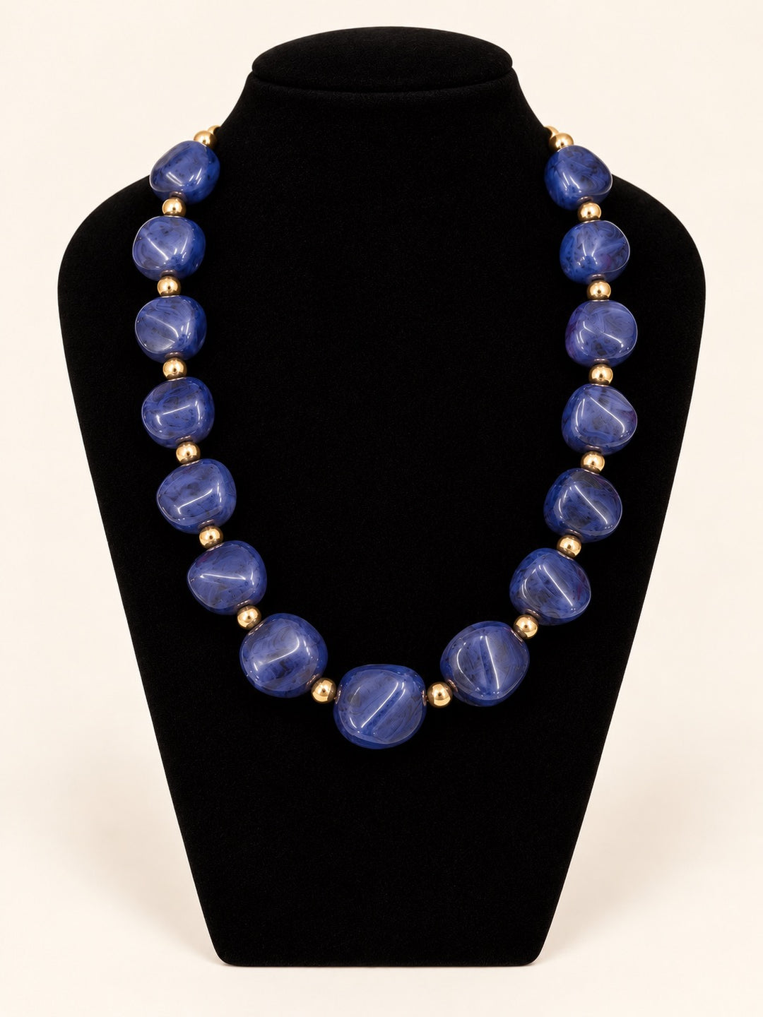Lindon Blue Statement Beaded Necklace featuring vibrant cobalt blue resin beads and gold-tone spacer accents displayed on black velvet.