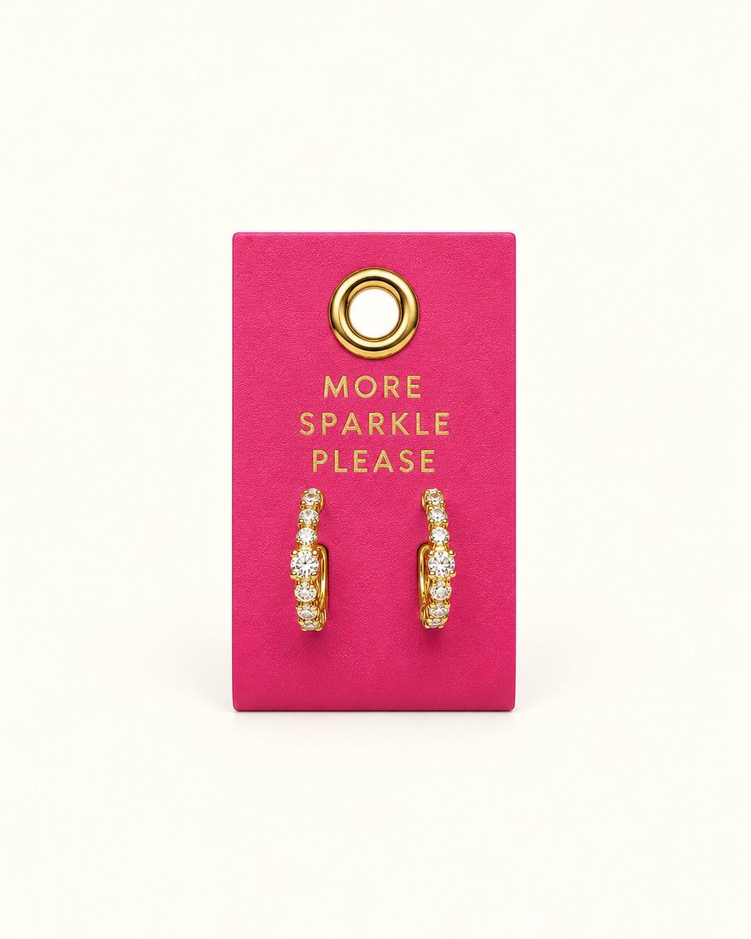 Gold-tone petite hoop earrings lined with sparkling clear crystals displayed on a bright pink More Sparkle Please Palm Beach leather jewelry tab