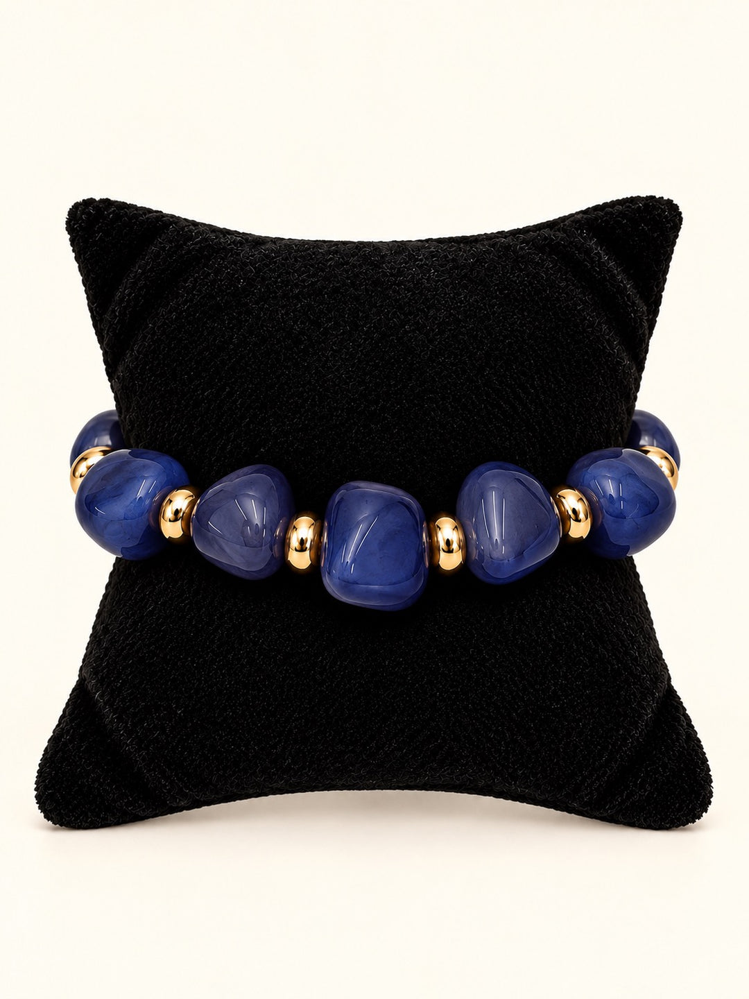 Lindon Blue Beaded Statement Bracelet featuring vibrant cobalt blue resin beads and gold-tone spacers displayed on a black velvet jewelry pillow.