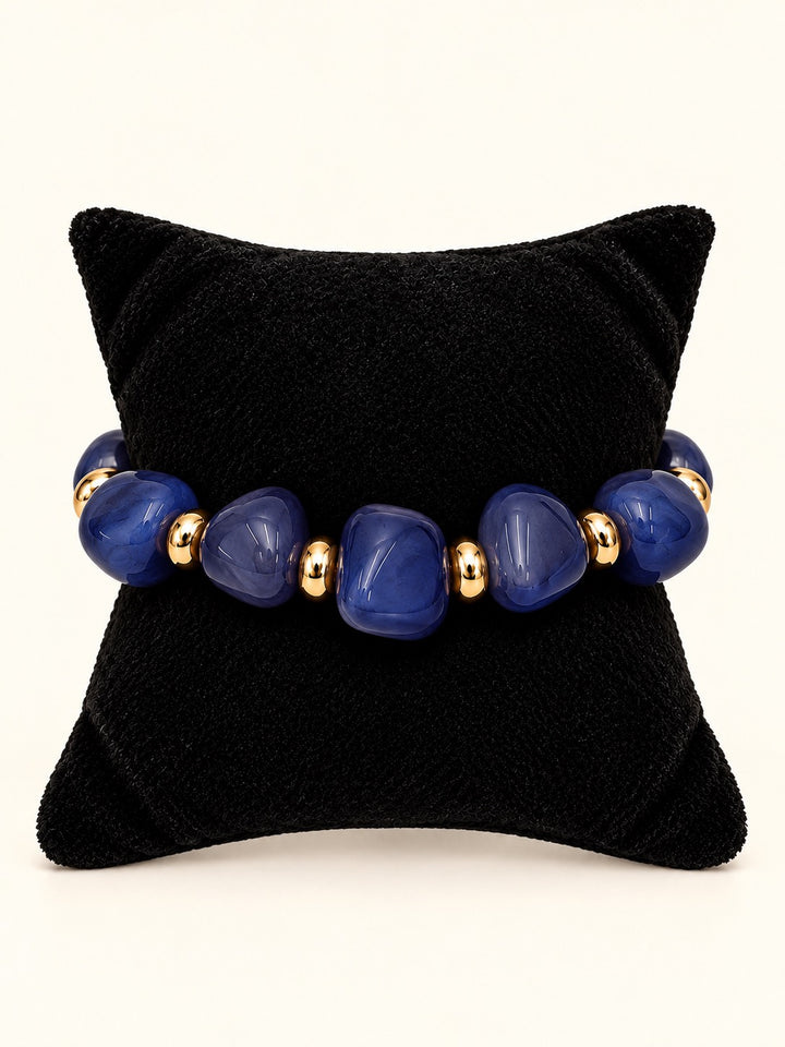 Lindon Blue Beaded Statement Bracelet featuring vibrant cobalt blue resin beads and gold-tone spacers displayed on a black velvet jewelry pillow.