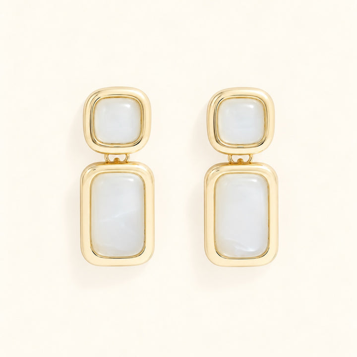 Close-up of Laurel Cream statement earrings with square resin studs and elongated rectangular drops framed in polished gold-tone metal.