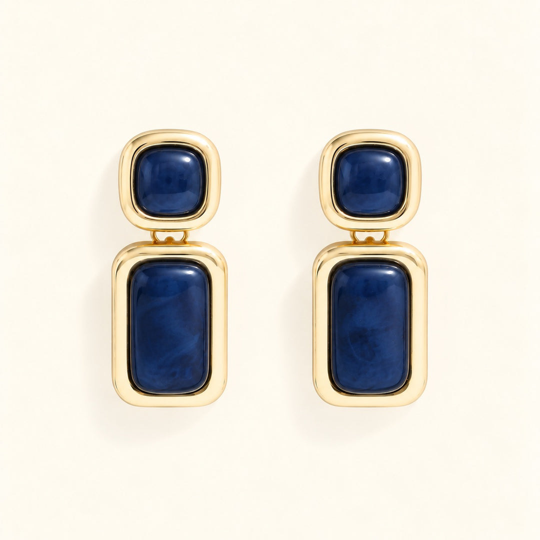 Close-up of Laurel Blue statement earrings featuring glossy navy resin stones, square studs, and rectangular gold-tone drops.