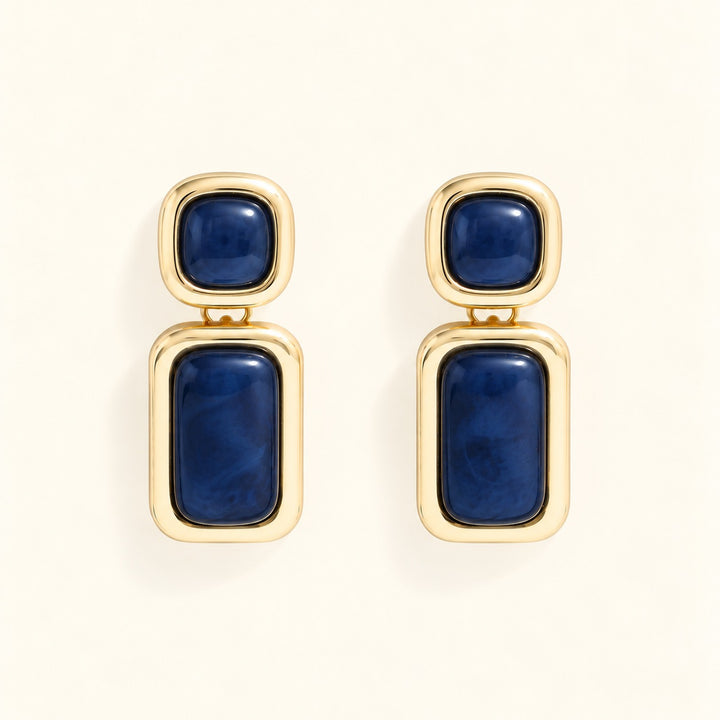 Close-up of Laurel Blue statement earrings featuring glossy navy resin stones, square studs, and rectangular gold-tone drops.