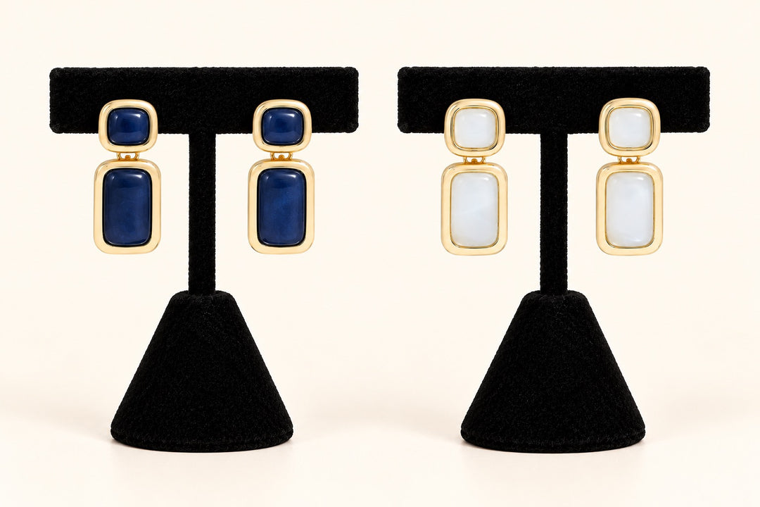 Laurel statement drop earrings in Blue and Cream featuring gold-tone rectangular frames displayed on two black velvet earring stands against a cream background.