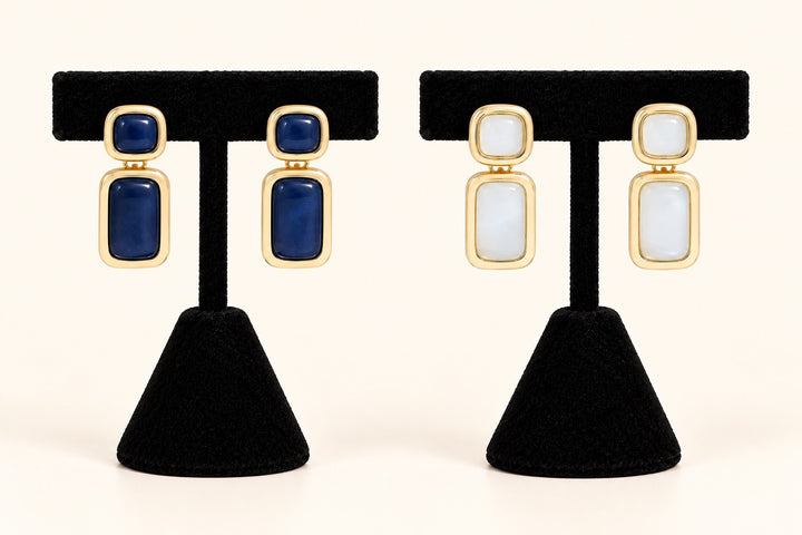 Laurel statement drop earrings in Blue and Cream featuring gold-tone rectangular frames displayed on two black velvet earring stands against a cream background.