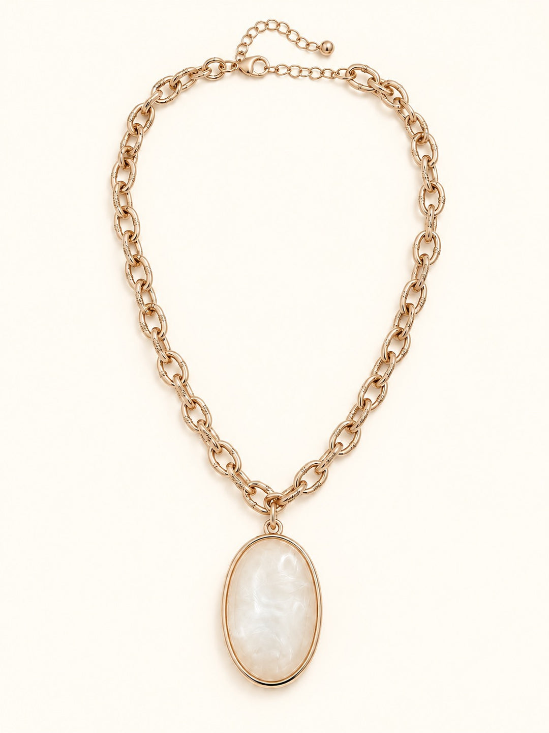 Susannah Gold Pendant Necklace laid flat on a cream background, showcasing its oval cream pendant, textured gold-tone chain, lobster clasp, and adjustable extender.