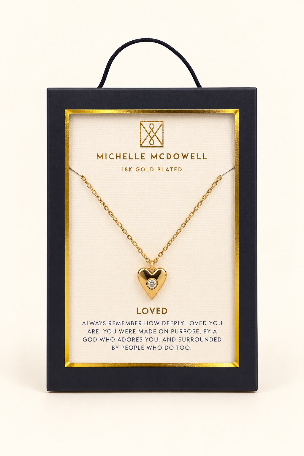 Michelle McDowell Loved Gold Heart Necklace displayed in branded gift packaging with an inspirational Loved sentiment card, featuring an 18K gold-plated heart pendant and delicate chain.